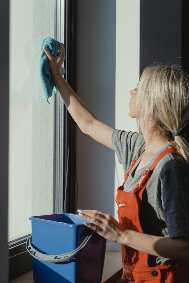 GURU® employee cleaning the top of a nightstand in a white bedroom