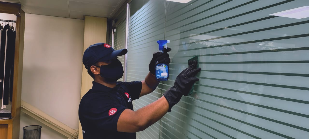Guru Cleaning Experts team member cleaning glass.